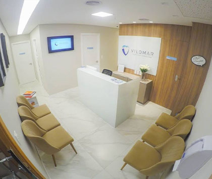 Ambiente da recepção da clínica odontológica, com espaço acolhedor e confortável para pacientes.